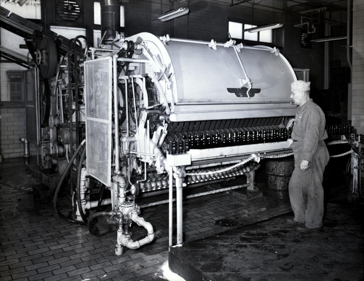 A man stands near a bottling machine
