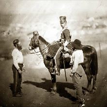 Soldier on his horse, two helpers stand nearby
