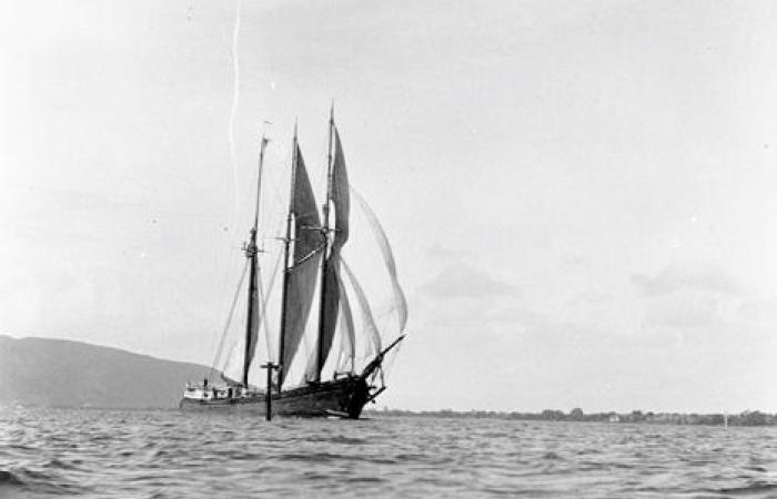 Black and white photo of a ship sailing on the ocean. There is no land in sight, just water.